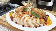 a white plate topped with sliced up turkey and oranges on top of a wooden cutting board