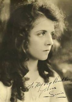 an old black and white photo of a young woman with long hair, looking off to the side