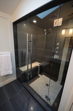 an image of a bathroom setting with black and white tile on the floor, shower stall and sink