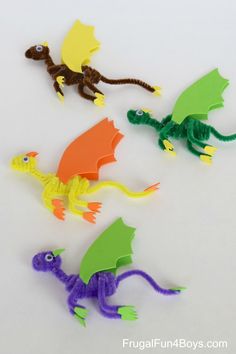 four plastic dragon figurines sitting next to each other on a white table top