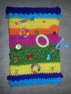 there is a crocheted square with buttons and pins on the bottom, along with other items