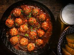 meatballs and gravy are in a skillet on a table next to bread