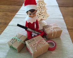 an elf is sitting on the table with presents