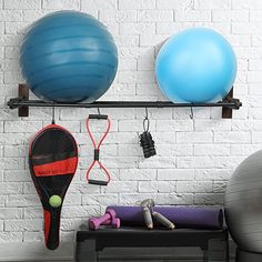 there are several exercise balls and equipment hanging on the wall next to eachother