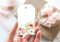 a person holding up a gift tag with flowers on it