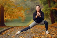 a woman is doing yoga outside in the fall