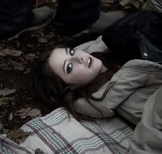 a young woman laying on the ground with her eyes wide open and looking at the camera