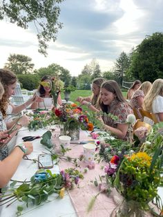 a group of women sitting around a table with flowers