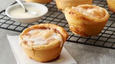 several pastries sitting on top of a cooling rack next to a bowl of sauce