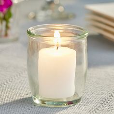 a lit candle in a glass jar on a table