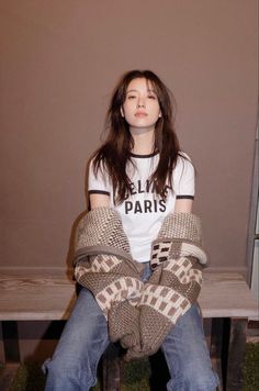 a woman sitting on top of a wooden bench wearing knitted mittens and a t - shirt