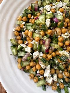 a white plate topped with cucumber, chickpeas and feta cheese