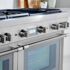 a stainless steel oven with four burners and two doors on the front, in a white kitchen