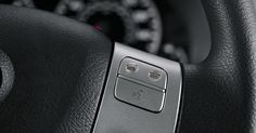 the steering wheel controls on a car with black leather and silver trims, including buttons