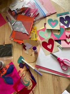 the table is covered with lots of crafting supplies and paper hearts that are on top of each other