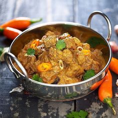 a metal pot filled with food next to carrots and celery on top of a table