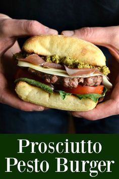 a person holding a sandwich in their hands with the words proscutto pesto burger on it