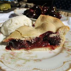 a piece of pie on a plate with ice cream and cherries