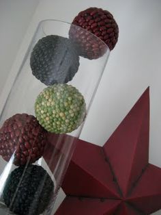 four balls in a glass vase on top of a red star