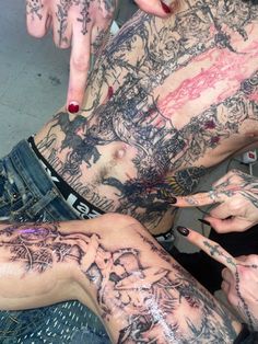 two people with tattoos on their bodies pointing at each other's fingernails