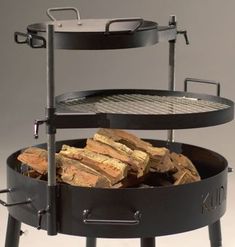 an outdoor charcoal grill with firewood stacked on the top and two racks holding it