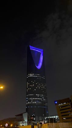 a very tall building with a bright blue light on it's side at night