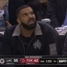 a man sitting in front of a basketball ball on top of a table next to other people