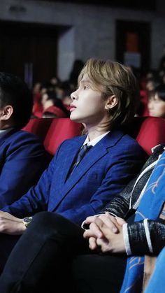 three people sitting in the front row of a movie theater, one with his head turned to the side