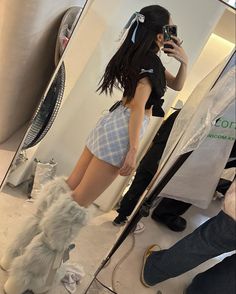 a woman taking a selfie in front of a mirror with her legs crossed and boots on