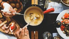 two people are cooking food on a stove with utensils in front of them