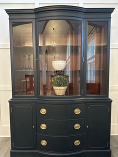 a black china cabinet with glass doors and gold trimmings on the bottom shelf