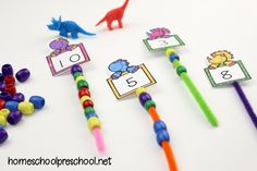 colorful pencils with numbers on them sitting next to each other in front of some dinosaur themed erasers