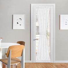 a dining room table and chairs in front of a white door with curtains on it