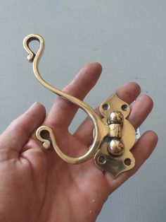 a hand holding a gold colored metal object in it's left hand, with the handle extended