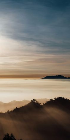 the sun shines brightly through the clouds in the distance, as seen from atop a mountain