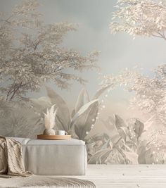 a white couch sitting in front of a wall mural with trees and plants on it