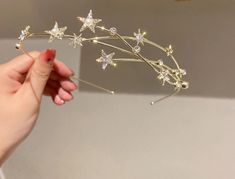 a person holding up a gold tiara with stars on the side and pearls in the middle