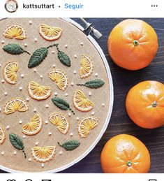 oranges and other fruit are on the table with an embroidered design in front of them