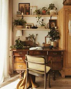 a desk with some plants on top of it and a chair in front of the desk