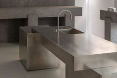 a stainless steel sink and counter in a room with fireplaces on the wall behind it