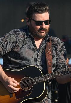 a man with sunglasses playing an acoustic guitar