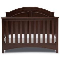 a brown crib with white sheets on the bottom and side rails, in front of a white background