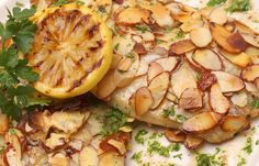 a white plate topped with fish covered in potatoes and garnish