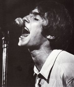 a man singing into a microphone while standing in front of a black and white photo