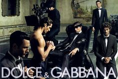 a group of men sitting next to each other in front of a poster for dolce & garbana