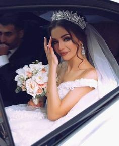 a bride sitting in the back seat of a car with her hand up to her face