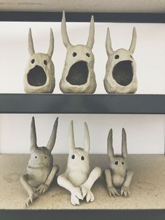 three sculptures of animals sitting on top of shelves