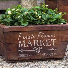 a wooden box with flowers in it sitting on gravel