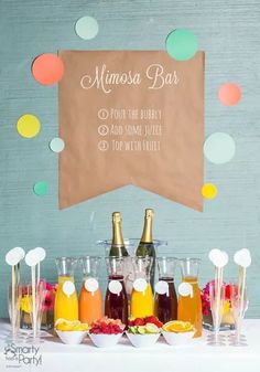 a table topped with bottles of drinks and glasses filled with fruit next to a sign that says mimosa bar