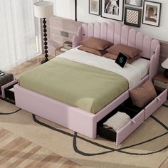 a pink bed with two drawers underneath it and some pictures on the wall above it